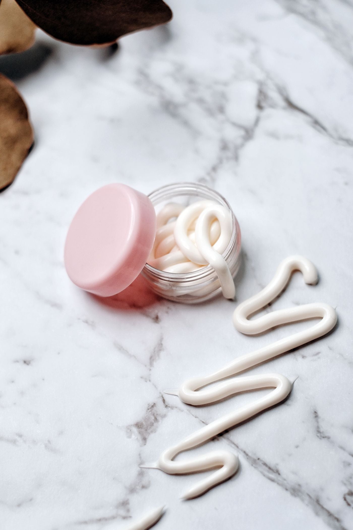 Open glass jar of mineral body cream on marble