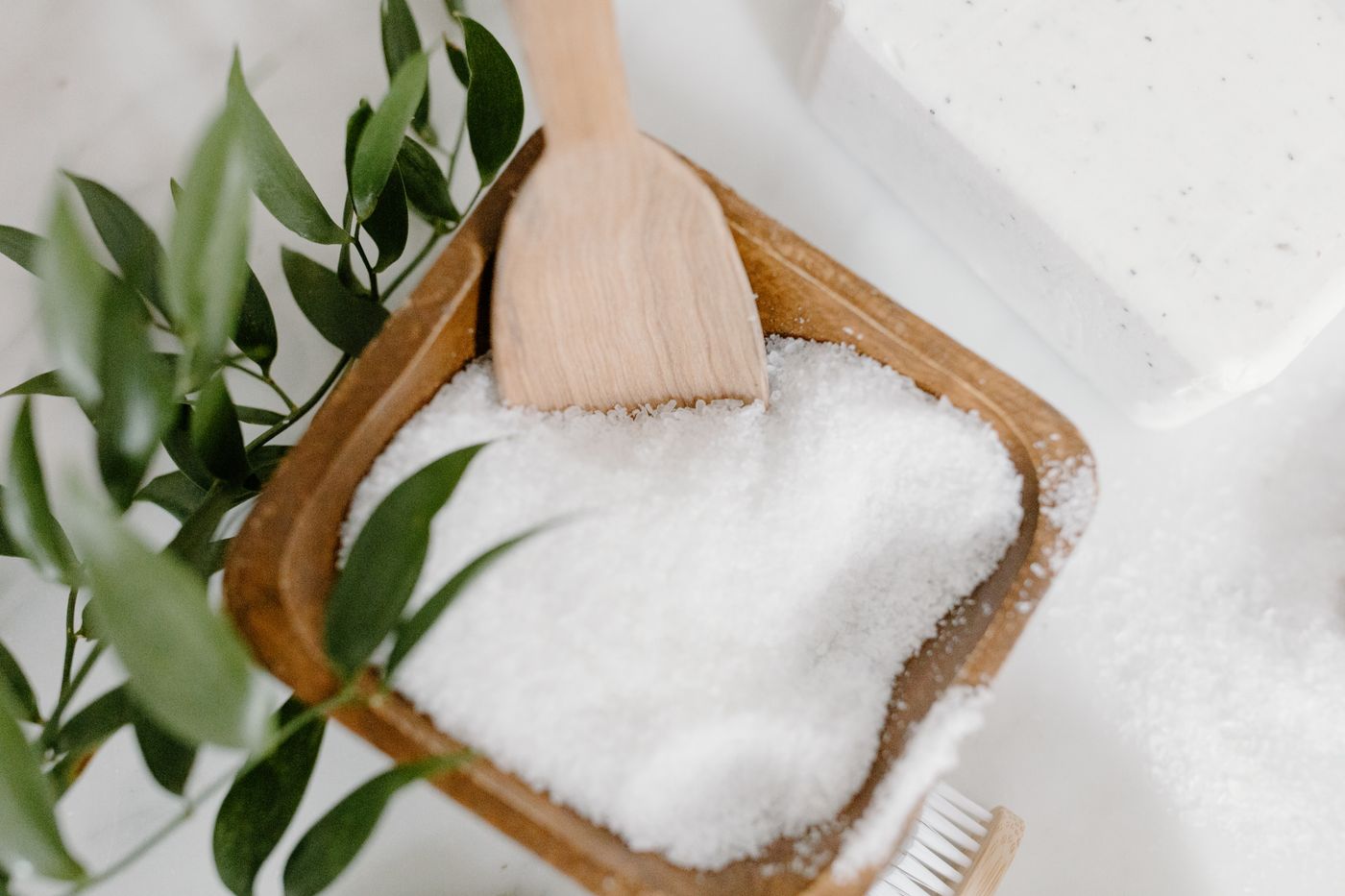 Coarse bath salts with wooden scoop on natural surface